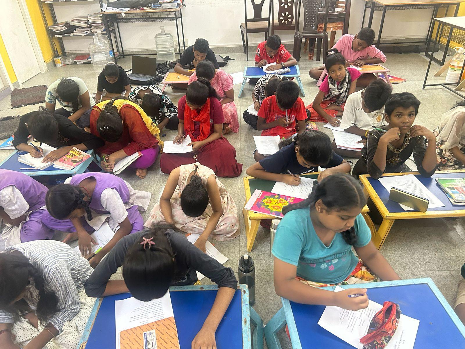 A room full of students working on worksheets on the floor