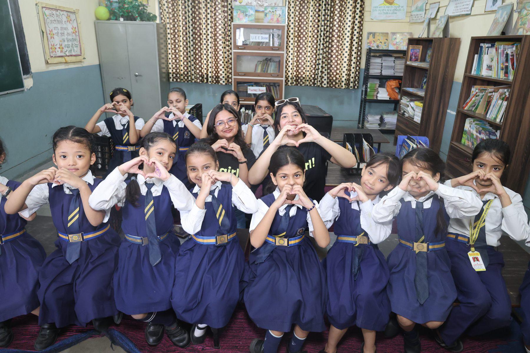 A class of girls making heart shapes with their hands