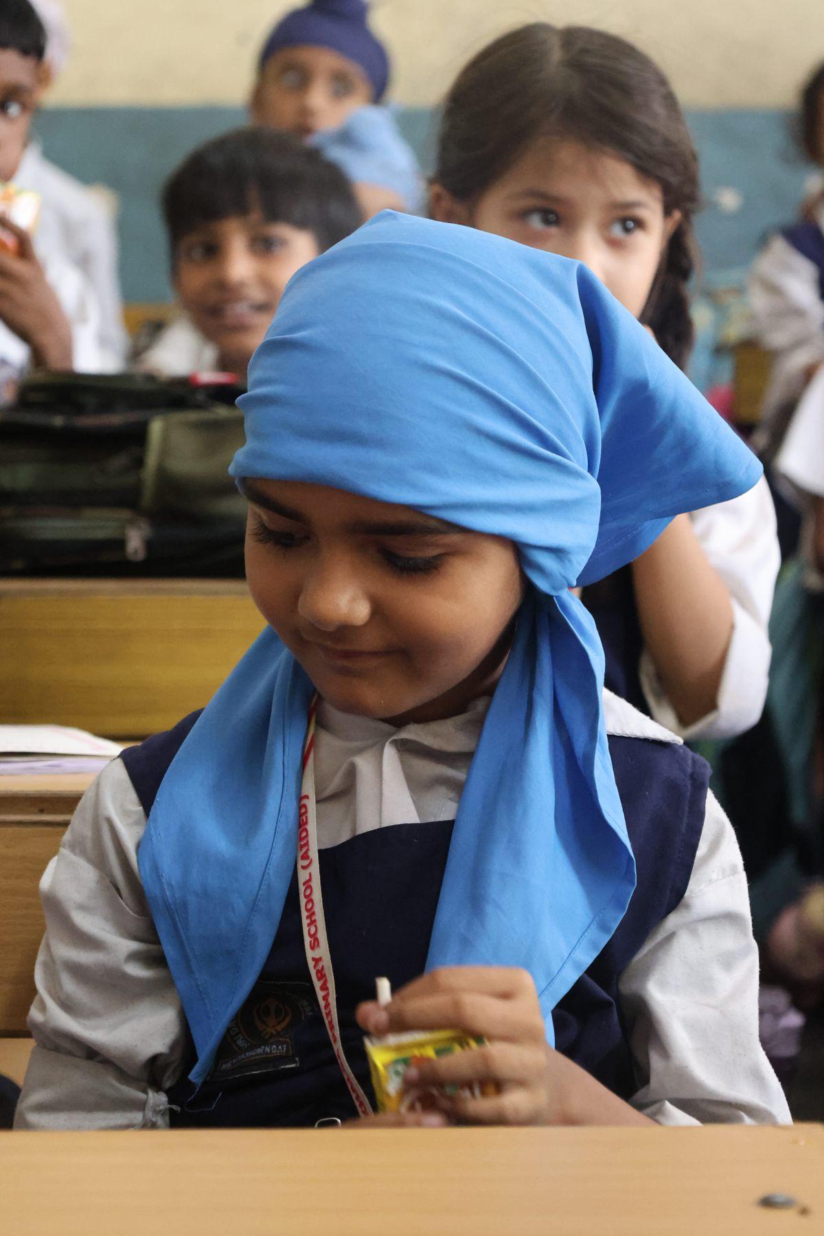A student in a blue headscarf at her desk